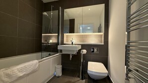 A modern bathroom with a bathtub, toilet, and sink. - Westminster Apartment - Big Ben (London)