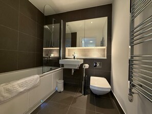 A modern bathroom with a bathtub, toilet, and sink. - Westminster Apartment - Big Ben (London)