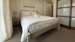 A bedroom with a bed, nightstands, a lamp, a painting, and a sliding door. - Westminster Apartment - Big Ben (London)