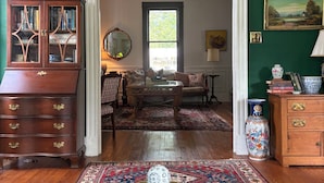 A room with a wooden cabinet, a mirror, a sofa, and a patterned rug. - Historic home in downtown Richmond by the James River (Richmond)