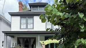 A two-story house with a porch, a wooden fence, and a garden area. - Historic home in downtown Richmond by the James River (Richmond)