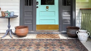 A turquoise door with a brass knocker, a black and white patterned rug, and two large pots on the porch. - Historic home in downtown Richmond by the James River (Richmond)