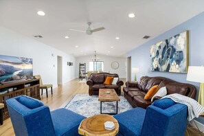 Ein geräumiges Wohnzimmer mit einem braunen Ledersofa, blauen Sessel und einem Holztisch.
