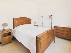 Un dormitorio con cama de madera, mesitas de noche, cómoda y radiador.