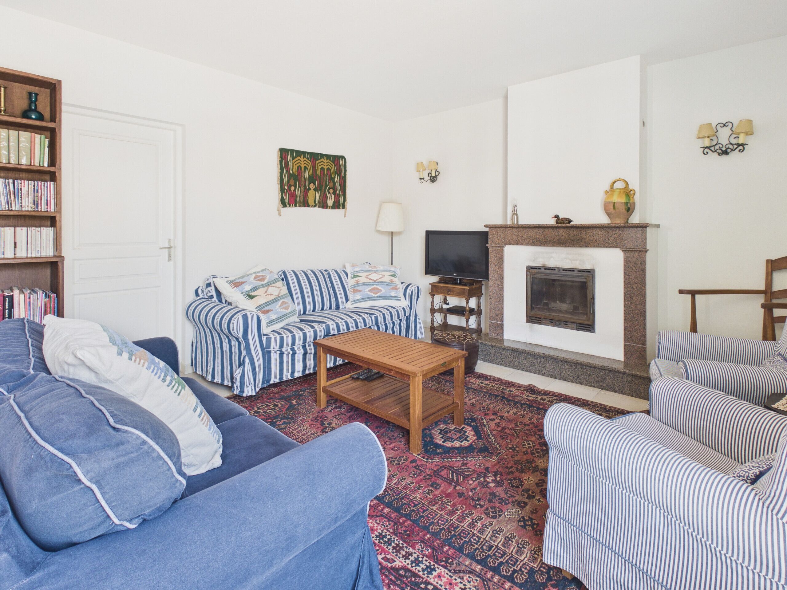 A living room with a sofa, armchair, and a fireplace.