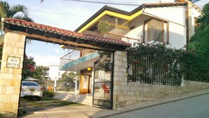 A two-story house with a gated entrance, a balcony, and a small attached garage. - VILLA LUZ house for rent in Mesitas del Colegio (El Colegio)
