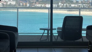 A balcony with a view of the beach and cityscape.