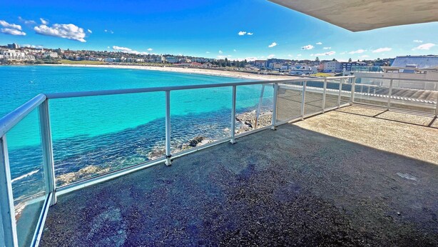 A balcony with a view of a beach and cityscape.