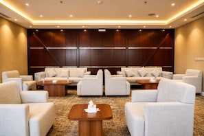 Habitación de hotel con zona de estar que incluye sofás y sillones, una mesa de centro de madera y piso alfombrado.