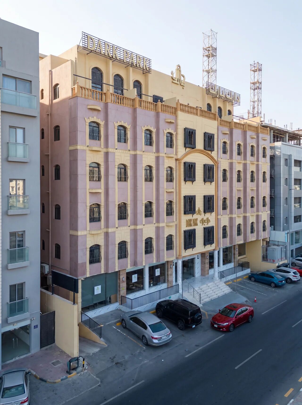 Un immeuble à plusieurs étages, sur lequel on peut lire l’inscription « DARK PARK ». Il se distingue par une entrée centrale avec un escalier, de nombreuses fenêtres et des balcons.