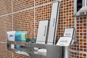 Un baño de hotel con espejo, kit de afeitado y artículos de aseo.