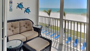 Un balcón con vista a la playa, un sofá y decoración de tortugas en la pared.