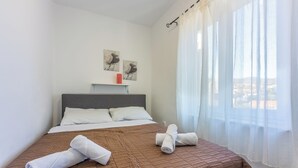 A neatly made bed with a brown quilt, white pillows, and two rolled towels on the bed. - Vacation apartment close to the beach with private parking and barbecue (Novi Vinodolski)