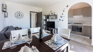 A dining area with a table set for four, a sofa, a kitchen with modern appliances, and a decorative wall with butterfly stickers. - Vacation apartment close to the beach with private parking and barbecue (Novi Vinodolski)