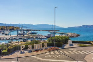 Un port de plaisance avec des bateaux amarrés, un ciel dégagé et des montagnes en arrière-plan.