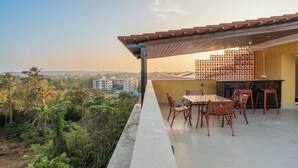 Una terraza con mesa y sillas, vista de la ciudad y un edificio al fondo.