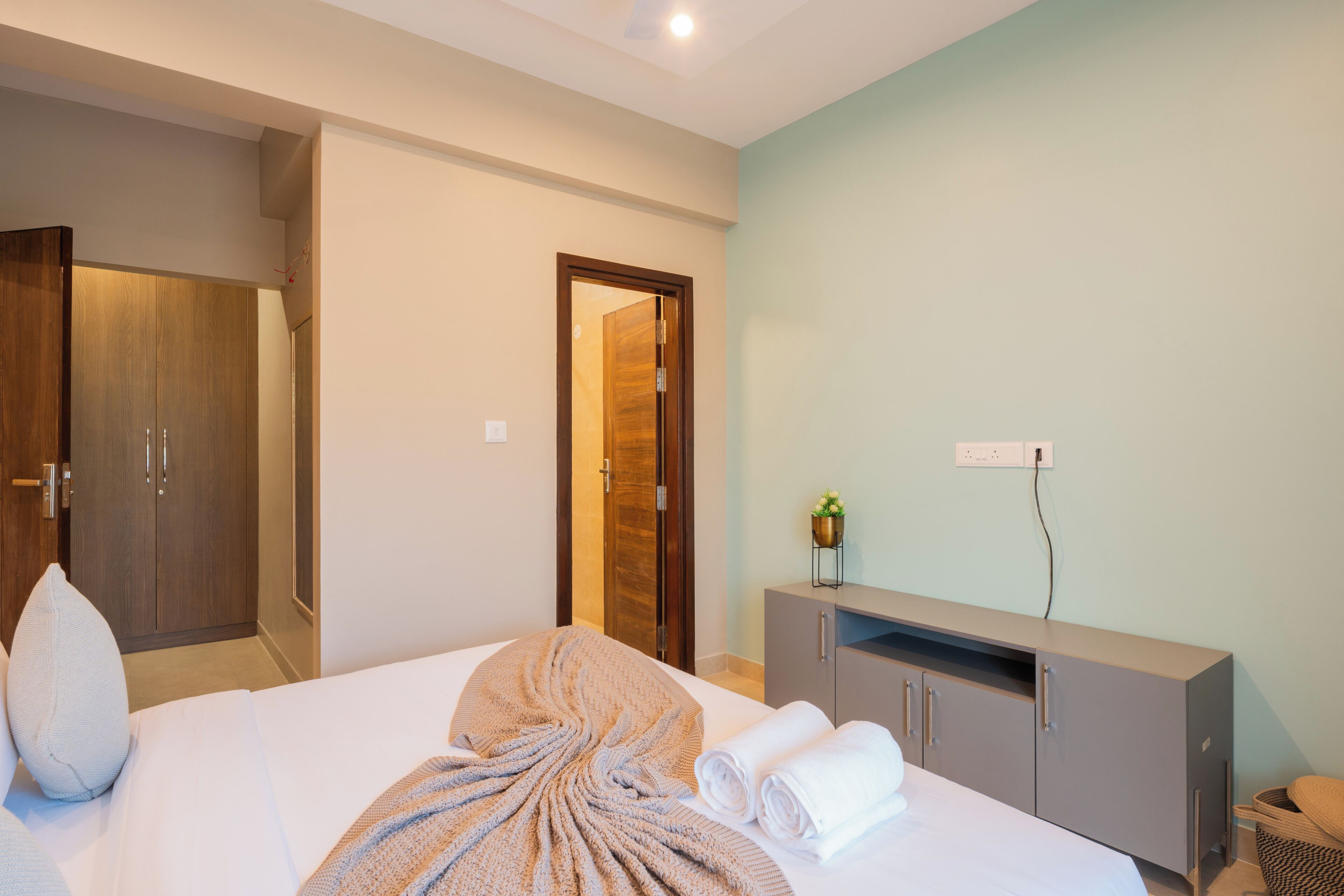 Ein Hotelzimmer mit einem Bett, einem Holzschrank, einem grauen Schrank und einer Steckdose.
