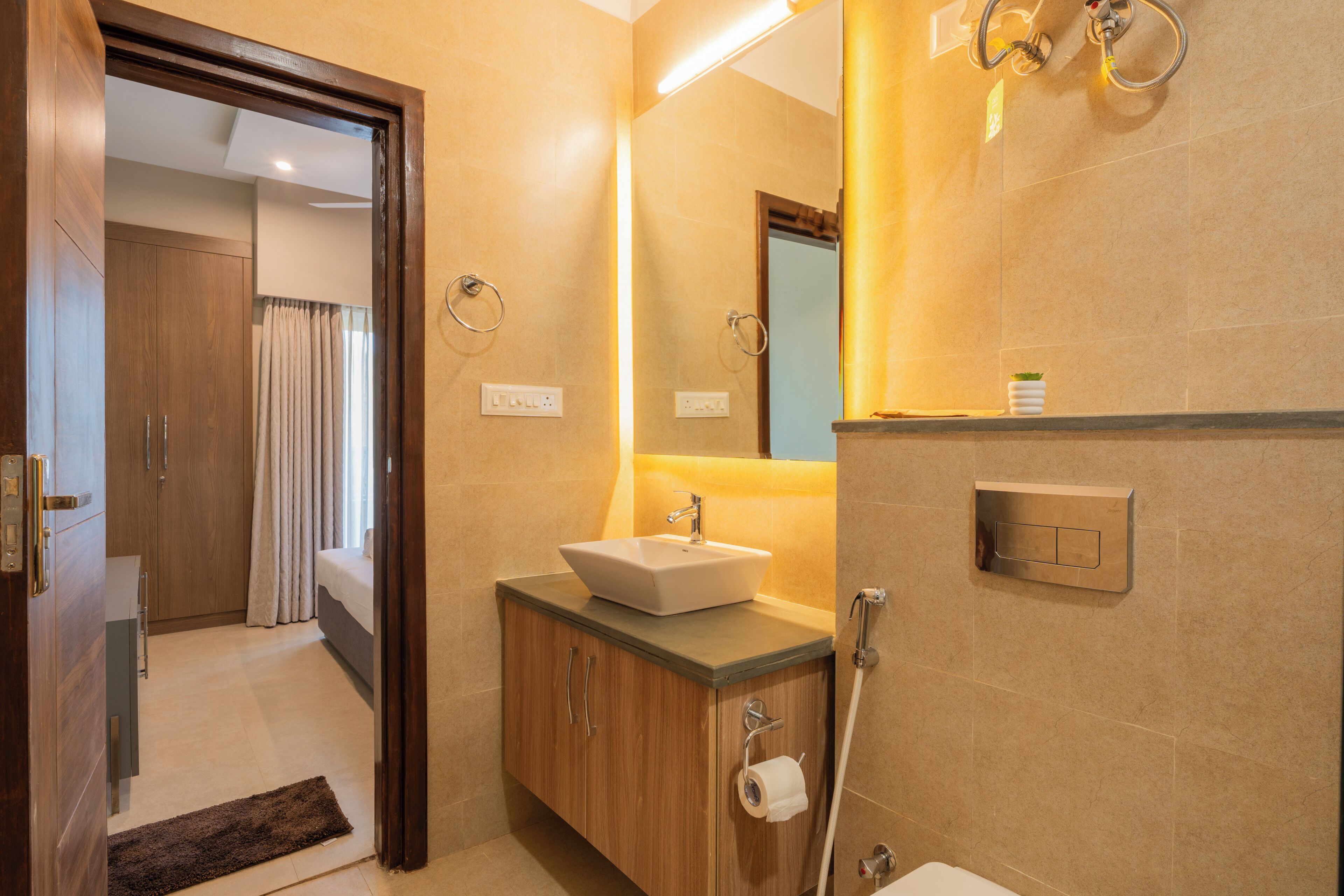 A modern bathroom with a wooden vanity, a white sink, and a mirror.