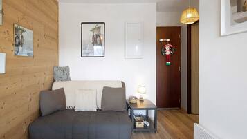 Un dormitorio con cama, mesita de noche, lámpara, puerta con letrero de bienvenida y un cuadro en la pared.