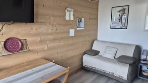 Una sala de estar con pared de madera, un sofá, una mesa y un televisor montado arriba.