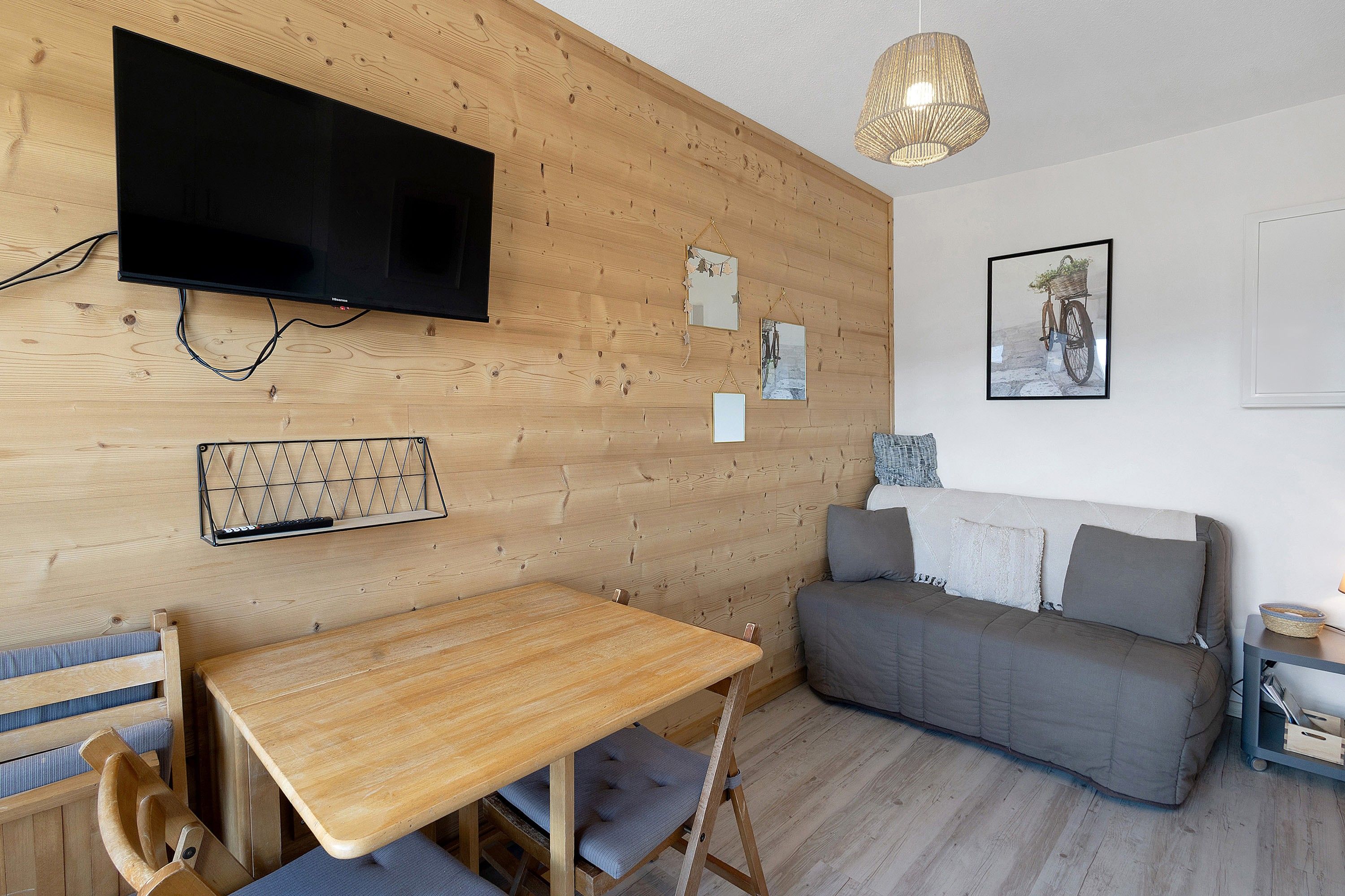 Habitación con paneles de madera, televisor, sofá, una mesa y decoración en las paredes.