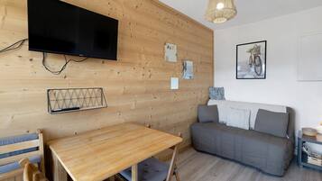 Habitación con paneles de madera, televisor, sofá, una mesa y decoración en las paredes.
