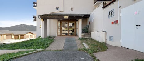 A building with a ground entrance, a covered area with a nameplate, and a garage door.