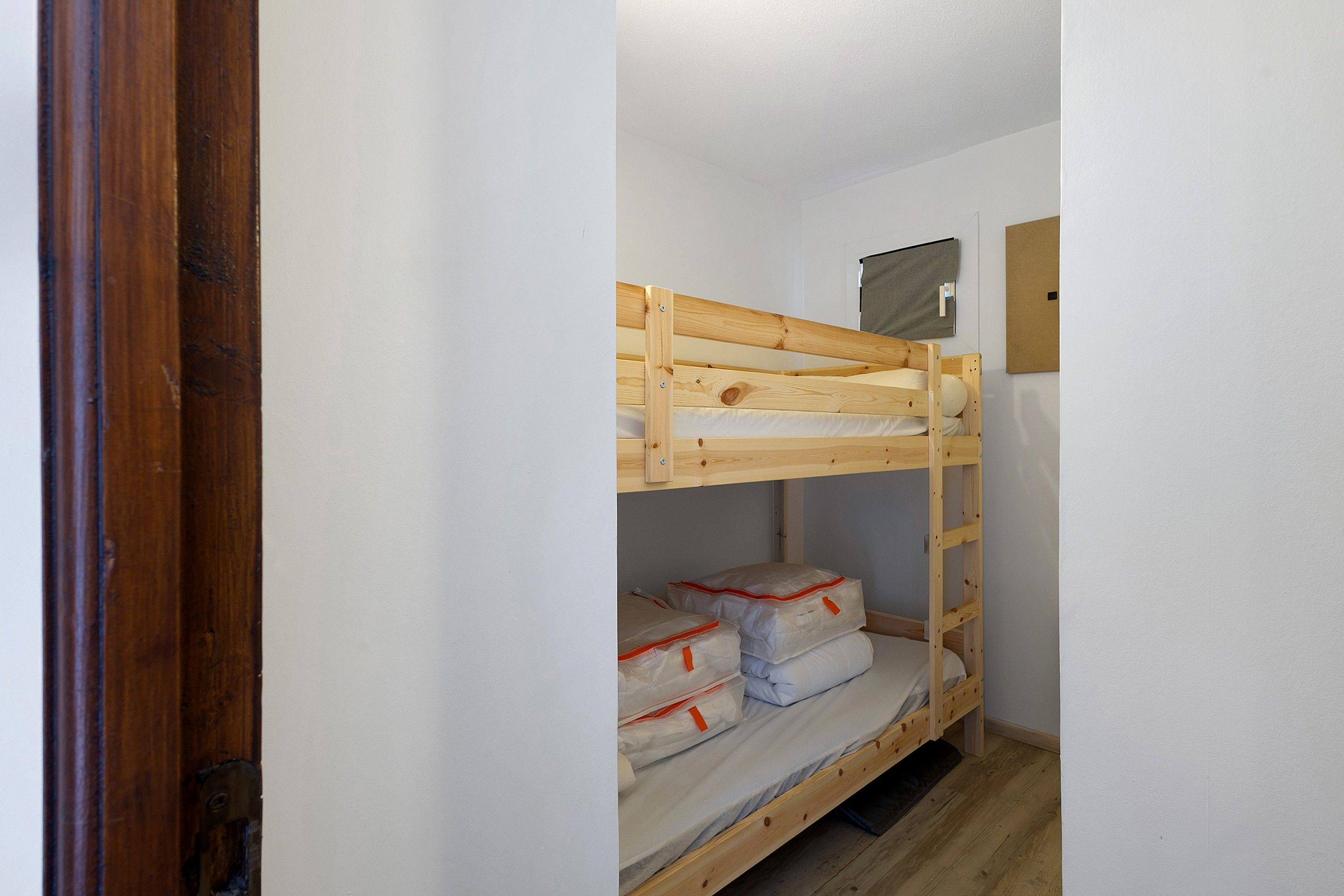 Una cama litera con estructura de madera, una litera inferior con colchón y almohadas, y un cabecero con una toalla colgada.