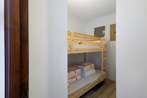 Una cama litera con estructura de madera, una litera inferior con colchón y almohadas, y un cabecero con una toalla colgada.