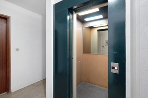 Un ascensor con panel de control, espejo y puerta con lámpara.