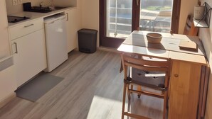 Una cocina moderna con armarios blancos, una mesa de comedor de madera y un ventanal con vistas a las montañas.