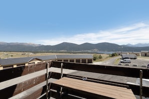 A view from a balcony overlooking a parking area with a mountain range in the distance. - Studio Apartment 'Soleil et Montagne' with Lake View and Balcony (Les Angles)