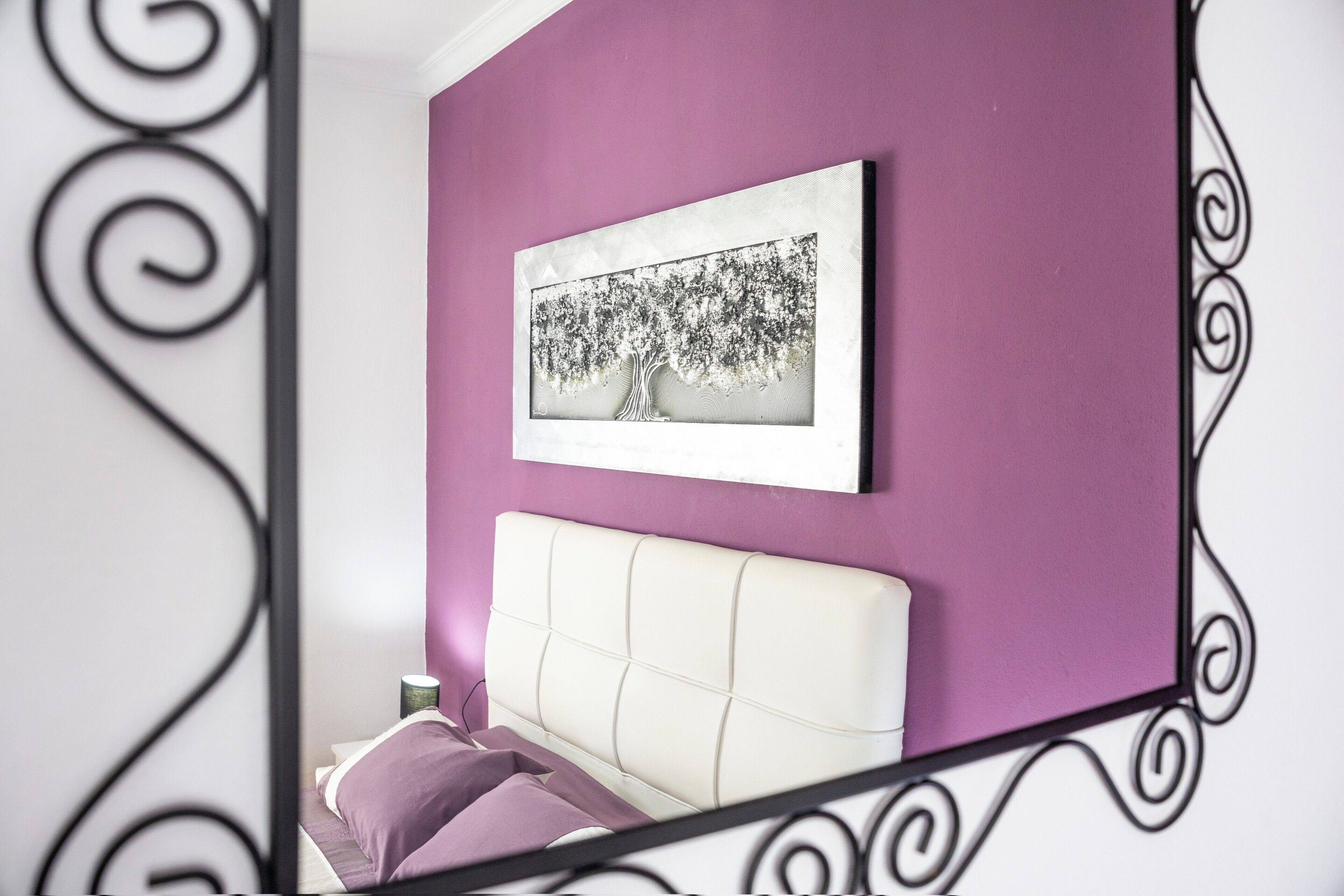 Une chambre à coucher comprenant un lit, un tableau accroché au mur et un cadre décoratif en métal.