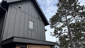 Ein rustikales Holzgebäude mit Veranda, einer Bank und einem Schild mit der Aufschrift 'BIGFOOT'S BUNKHOUSE'.