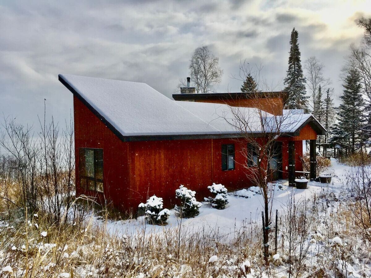 Ein rotes Holzhaus mit schneebedecktem Dach und einer kleinen Veranda.