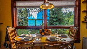 A dining table set for six with a bottle of wine, glasses, and plates.