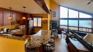 A kitchen with granite countertops, wooden cabinets, and pendant lighting.