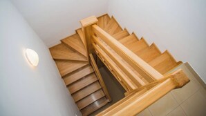 Un escalier en colimaçon en bois, doté d’une rampe et d’un luminaire fixé au mur.