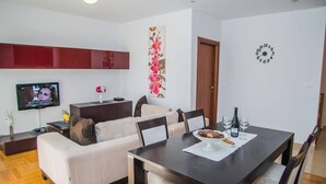 Un salon moderne comprenant un canapé, un téléviseur, une table à manger et des objets de décoration.