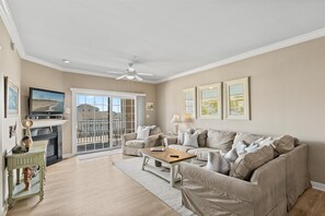 A living room with a sofa, coffee table, and fireplace. - Sea Bright 203 by Seaside Vacations & Sales (Ocean City)