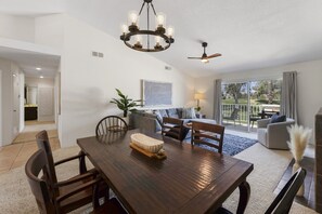 A dining area with a wooden table, chairs, a chandelier, and a ceiling fan. - Desert Falls Fairway Retreat (Palm Desert)