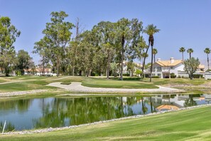 A golf course with a pond, trees, and a building with a tiled roof. - Desert Falls Fairway Retreat (Palm Desert)