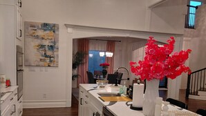 Una cucina moderna con isola centrale, pavimento in legno e lampadario.