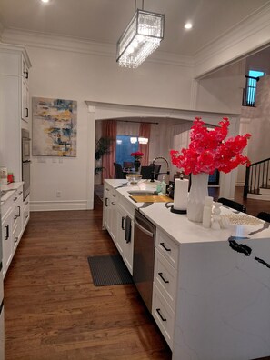 A modern kitchen with a central island, wooden flooring, and a chandelier. - World Cup FIFA Multi Family Retreat Near Airport (Atlanta)
