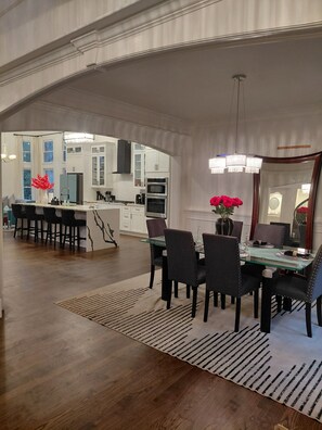 A spacious kitchen with white cabinets, a central island, and a dining area with a glass table and chairs. - World Cup FIFA Multi Family Retreat Near Airport (Atlanta)