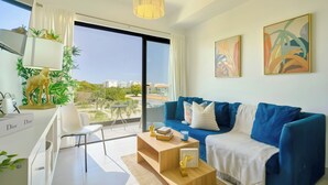 A modern living room with a blue sofa, a wooden coffee table, and a view of the outdoors.