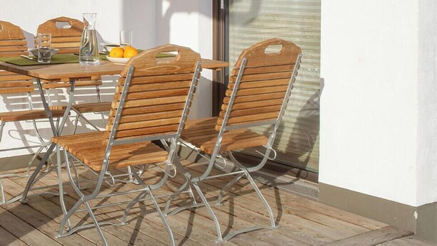 An outdoor dining area with a table, chairs, and a glass of orange juice. - NaturLogis-Allgäu in the organic claywood house Healthy living - living without pollutants (Nesselwang)
