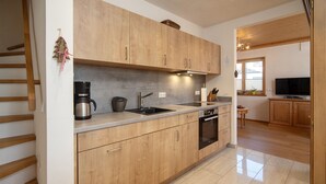 A modern kitchen with wooden cabinets, a built-in oven, a coffee maker, and a sink. - NaturLogis-Allgäu in the organic claywood house Healthy living - living without pollutants (Nesselwang)