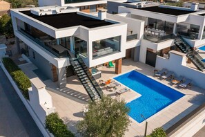 A modern multi-story building with a rooftop pool, outdoor seating, and a staircase leading to the upper levels. - Vivi Rent - Villa Old Olive I (Vodnjan)