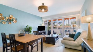 A living room with a TV, sofa, and dining area with chairs. - Juan-les-Pins Vitoria Grand 2P – Quiet, Parking, Central Location (Antibes)